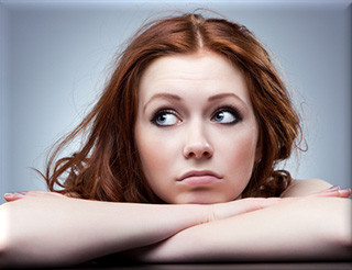 Young woman with arms folded under a sad looking face.