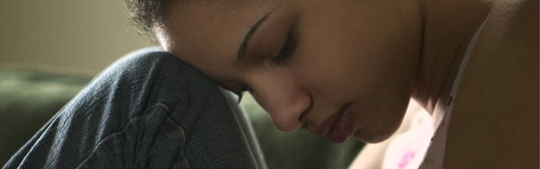 A young woman clenching bent over and clenching her knees