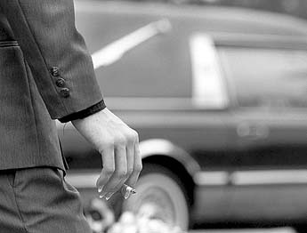 Smoker watching funeral  hearse drive away